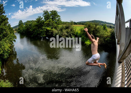 Un ragazzo adolescente salta da una passerella nel fiume Avon a Batheaston vicino a Bath in Somerset come le temperature si elevano in tutto il Regno Unito. Ondata di caldo. Foto Stock