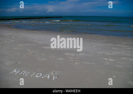 Happy Holiday, iscrizione da conchiglie sulla riva del mare. La sabbia bianca e mare blu. Foto Stock