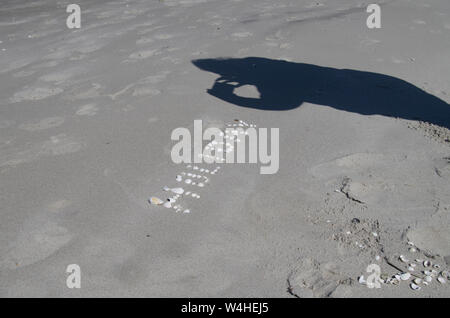 Iscrizione di conchiglie sulla sabbia e ombra di fotografare i turisti. Vacanza in spiaggia. Foto Stock