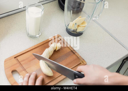 Un giovane uomo si prepara un frullato di latte e frutta fresca per la colazione. Egli conduce uno stile di vita sano. Foto Stock