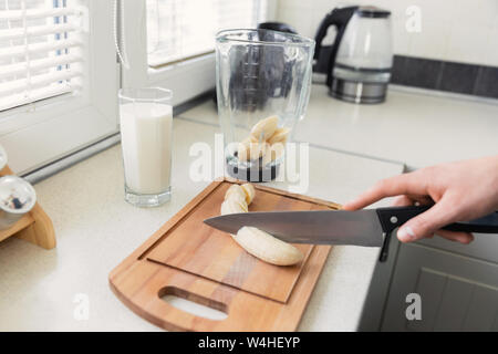 Un giovane uomo si prepara un frullato di latte e frutta fresca per la colazione. Egli conduce uno stile di vita sano. Foto Stock