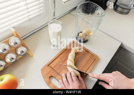 Un giovane uomo si prepara un frullato di latte e frutta fresca per la colazione. Egli conduce uno stile di vita sano. Foto Stock