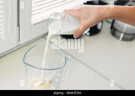 Un giovane uomo si prepara un frullato di latte e frutta fresca per la colazione. Egli conduce uno stile di vita sano. Foto Stock