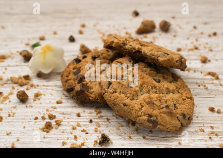 I biscotti al cioccolato accanto a un fiore su una tavola di legno Foto Stock