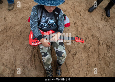 Un ragazzino con piccola chitarra con i genitori su open-air festival rock Nashestvie nella regione di Tver, Russia Foto Stock