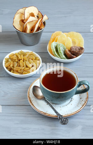 Dessert vegetariano: pezzi di canditi di ananas, kiwi, radice di zenzero e mango, di fichi secchi e di uva passa dorata, chip Apple in piccole ciotole e una tazza di blac Foto Stock