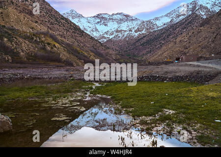 Bel tramonto su Jebel Toubkal montagna in Alto Atlante Marocco Africa con la riflessione sull'acqua Foto Stock