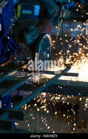 Fabbro di taglio tubo di ferro con mola. Concetto blacksmithing. Foto Stock