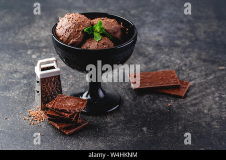 Tre brown di gelato al cioccolato sfere nella ciotola nero su sfondo scuro Foto Stock