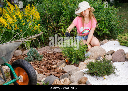 Bambina per aiutare i genitori in estate il giardino alpino coltivare il giardino di roccia imparare a fare lavori di giardinaggio Foto Stock