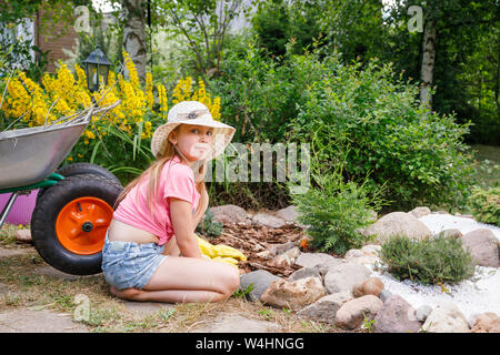 Bambina per aiutare i genitori in estate il giardino alpino coltivare il giardino di roccia imparare a fare lavori di giardinaggio Foto Stock