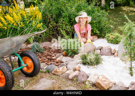 Bambina per aiutare i genitori in estate il giardino alpino coltivare il giardino di roccia imparare a fare lavori di giardinaggio Foto Stock