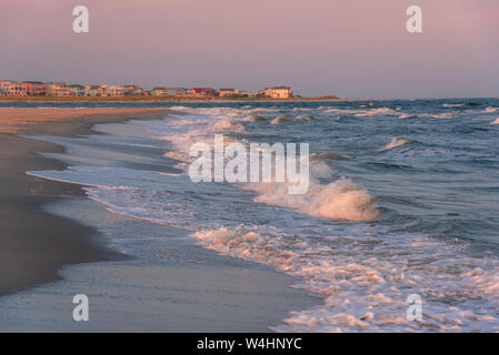 Case sulla spiaggia e le onde del mare al tramonto, Holden Beach, Carolina del Nord, Stati Uniti Foto Stock