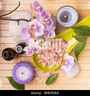 Spa.Composition con fiori di orchidea, alcune piccole bottiglie con olio essenziale di rosa, sali, candele e pietre di luce per il massaggio Foto Stock