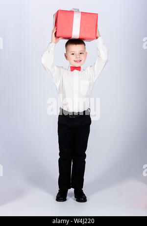 Tuxedo stile. Infanzia felice. Festa di compleanno. Shopping. Boxing day. Anno nuovo ragazzino con il giorno di san valentino regalo. Bambino contento con la presente casella. Natale. shop assistant dando pacchetto il pacchetto. Foto Stock