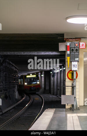 Nordbahnhof, Berlin, Germania - Luglio 07, 2019: vista dalla piattaforma nel illuminato tunnel ferroviario con un treno che si avvicina a distanza Foto Stock