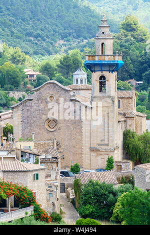 Dettaglio colpo di Esglesia de Sant Bartolomeu nella città vecchia di Valldemossa (La Maiorca, Spagna), circondato da verdi alberi in montagna Foto Stock