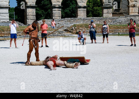 I turisti guarda come attori fase gladiator battaglia in Arena di Pola, un anfiteatro romano costruito in Croazia nel I secolo d.c. Foto Stock