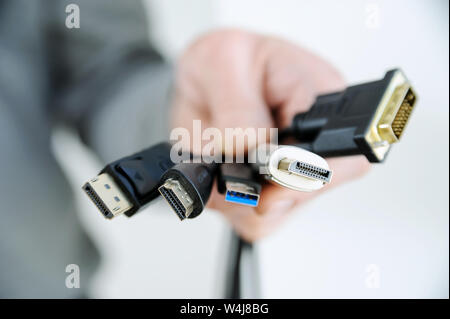 Vi sono diversi cavi e spine nella mano di un uomo. Foto Stock