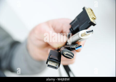 Vi sono diversi cavi e spine nella mano di un uomo. Foto Stock