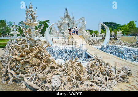 Scary scena, raffigurante l'inferno, il caos e l'orrore di fronte bianco (tempio Wat Rong Khun), centinaia di creepy mani, teschi e creature mitico luogo Foto Stock