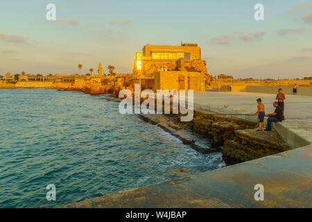 Cesarea, Israele - 22 Luglio 2019: vista al tramonto del vecchio porto con i pescatori e con gli altri visitatori, a Cesarea National Park, Nord di Israele Foto Stock