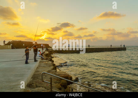 Cesarea, Israele - 22 Luglio 2019: vista al tramonto del vecchio porto con i pescatori e con gli altri visitatori, a Cesarea National Park, Nord di Israele Foto Stock