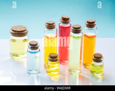Essenza colorate le bottiglie di olio su sfondo bianco Foto Stock
