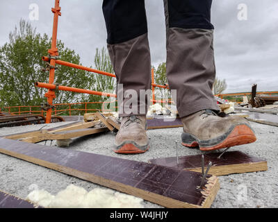 Un lavoratore edile ha un incidente mentre passeggiate attraverso un sito con i detriti e salendo su un chiodo. Foto Stock