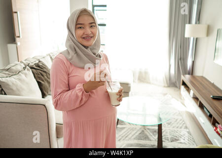 Musulmani donna incinta asian bere latte Foto Stock