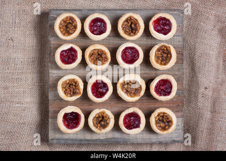 Noci pecan in miniatura e apple cranberry la torta su un weathered legno e tela sfondo Foto Stock