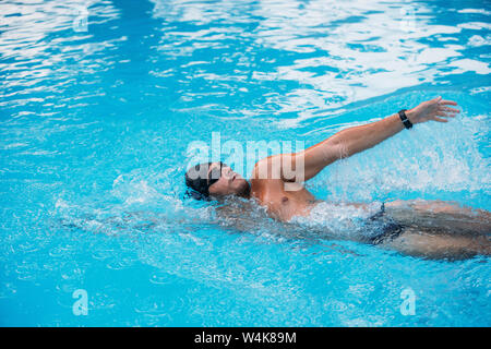 Atletica Giovane uomo nuoto sul dorso di stile. Il nuoto della concorrenza. Foto Stock