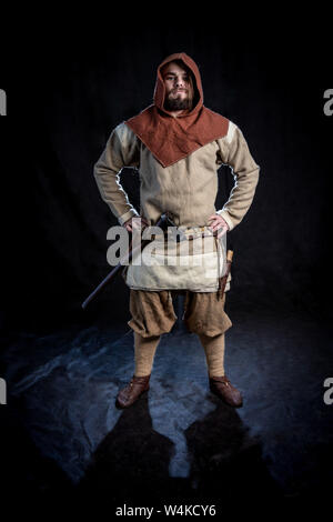 Viking in abiti casual e il cofano mantenendo un'ascia sulla cinghia. ricostruzione storica del basso medioevo Foto Stock