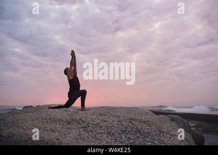 L'uomo facendo il cresent lunge pongono dall'oceano Foto Stock