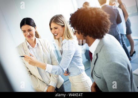 Lavoro di squadra creativa nella parte anteriore della parete di vetro utilizzando post-it e adesivi Foto Stock