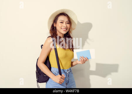 Ritratto di giovane donna che indossa abiti alla moda, cappello di paglia, viaggi con zaino e tenendo il biglietto di volo, Passport Foto Stock