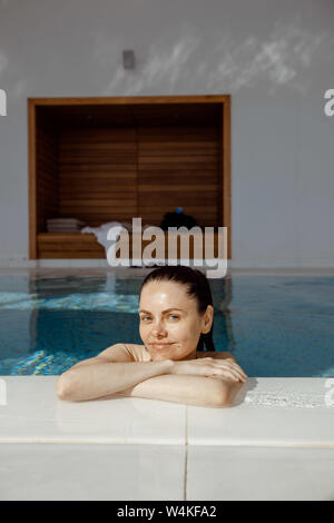 Donna sorridente di riposo in piscina Foto Stock