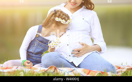 Gravidanza madre e figlia piccola avente un picnic nel parco in una giornata di sole. La foto ha un spazio vuoto per il testo Foto Stock