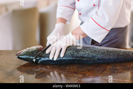 Lo chef taglia il salmone sul tavolo. Foto Stock
