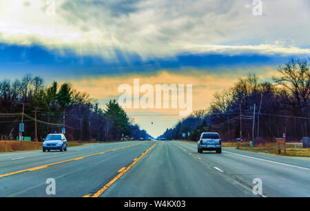 Strada e sky convergenti nell'orizzonte. I veicoli che esercitano su di Michigan del nord autostrada sotto una radiosa del cielo della sera. Foto Stock