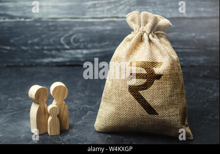 Miniatura in legno figurine famiglia stare vicino a un sacco di denaro. Il concetto di risparmio. Pianificazione del bilancio. Reddito familiare. Distribuzione degli utili. Financial m Foto Stock