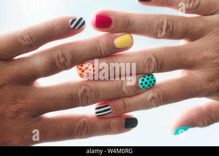 Una coppia di mani femminili con colorate unghie verniciate con diverse configurazioni Foto Stock