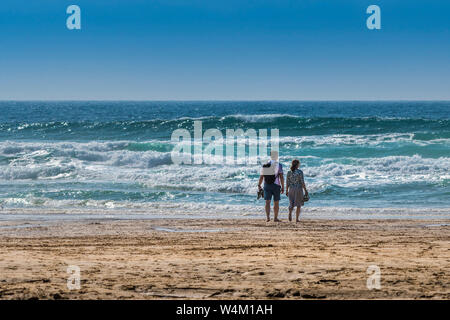 I turisti in piedi sul litorale affacciato sul mare su Fistral Beach in Newquay in Cornovaglia. Foto Stock