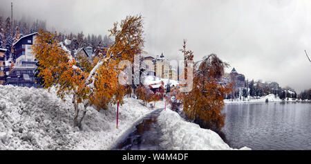 Scenic autunno vista con la prima neve su una sporcizia strada bagnata in montagna, alberi e foresta nella neve e brina sullo sfondo di un overcas Foto Stock