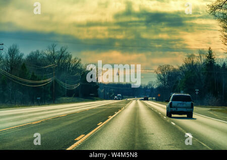 Le vetture che esercitano su una regione del Nord della superstrada del Michigan, USA, sotto una drammatica del cielo della sera. Foto Stock