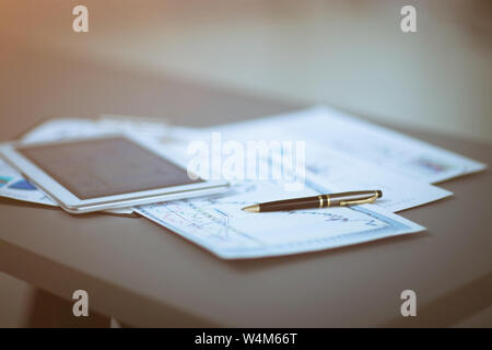 Tablet PC e grafici finanziari, penna giacente sul documento Foto Stock