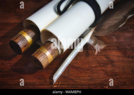 Close-up di vecchio stile di scorrimento della carta con una piuma quill penna su una tavola di legno Foto Stock