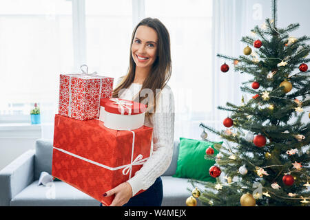 Donna allegra con i regali di Natale per la famiglia in decorate home Foto Stock