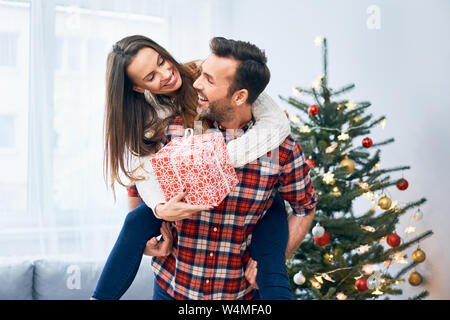 Allegro giovane tenendo presente e goofing intorno a Natale decorato soggiorno Foto Stock