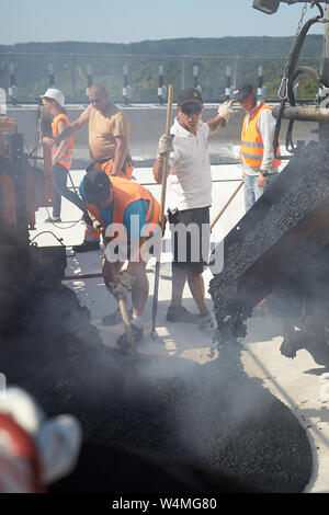 24 luglio 2019, Renania-Palatinato, Zeltingen-Rachtig: i lavoratori asfalto la superficie stradale del ponte Hochmosel in costruzione a temperature ben al di sopra di 30 gradi Celsius. Non vi è alcun luogo ombroso su 160 metri di un edificio alto sopra la valle di Mosel. Foto: Thomas Frey/dpa Foto Stock